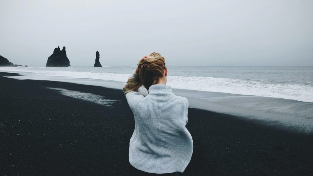 woman wearing sweater standing in front of beach